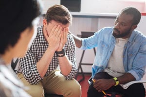 a man with his head in his hands upset at a mens addiction treatment program