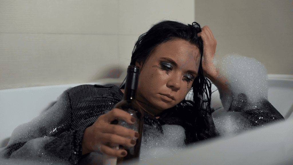 clothed woman drinking in a bathtub, alcohol and depression