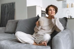 woman on couch smiling about inpatient vs outpatient treatment