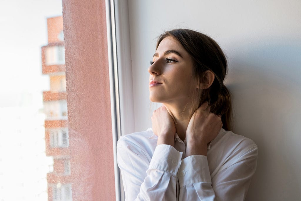 anxious woman standing near a window showing clear signs of drug use