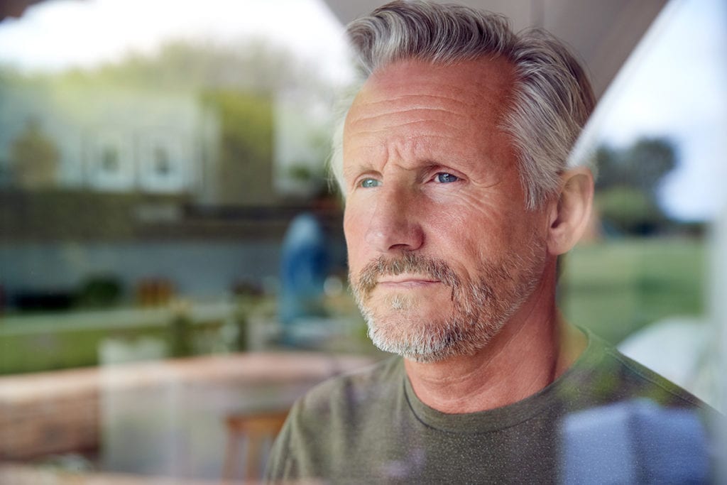 man staring out a window wonders how hard is it to quit drinking