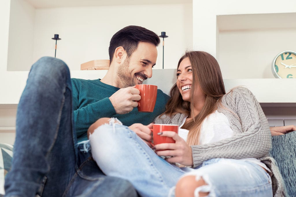 couple on couch laughing being quarantined with an alcoholic spouse