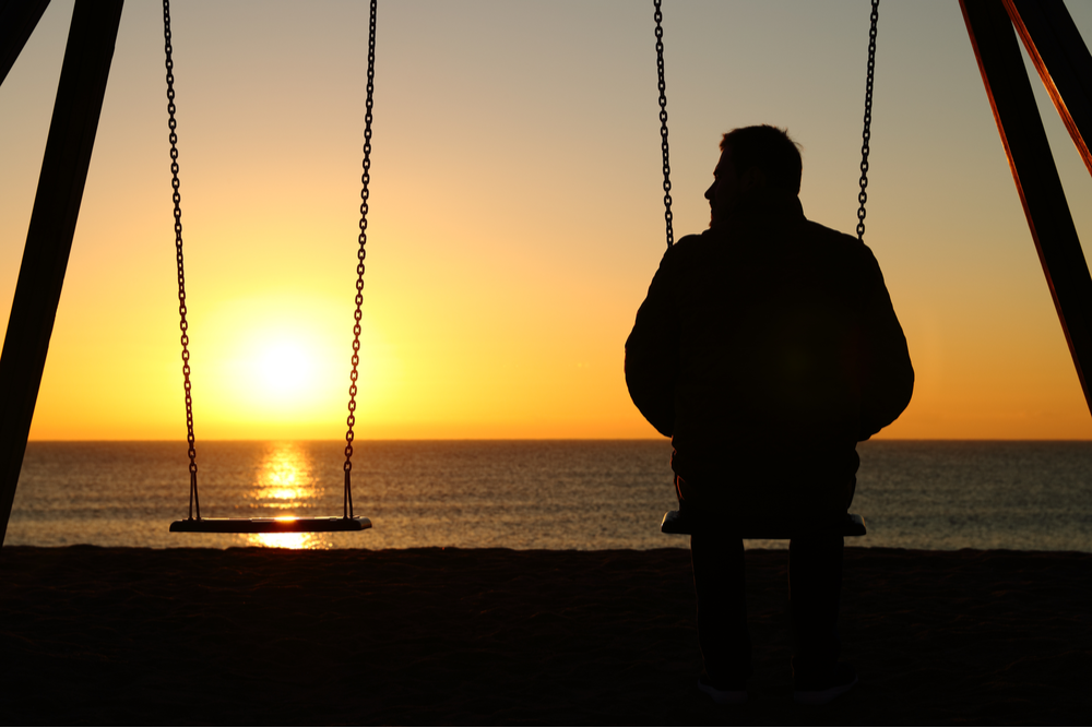 Man alone on a swing thinking of ways to overcome trauma