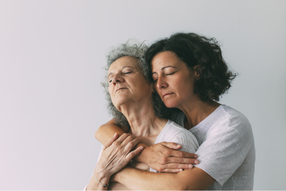 Woman hugging elderly mother living with genetics and mental health disorders