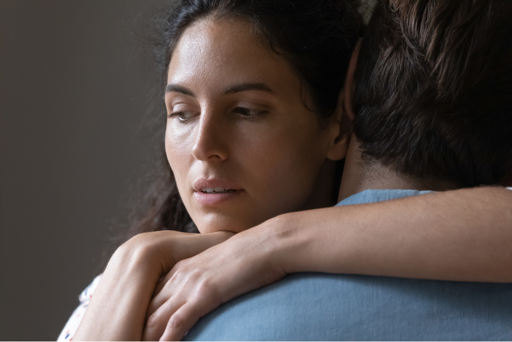 Woman hugging her spouse, unhappy due to people pleasing and trauma, wonders what is the fawn response