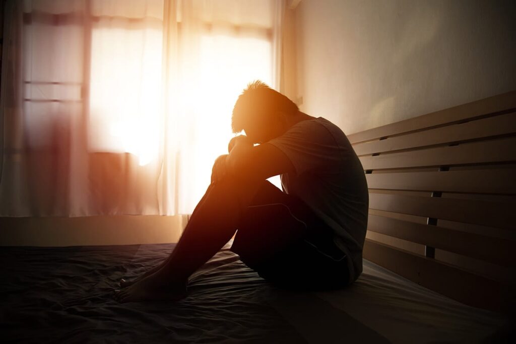 Silhouette of a person sitting on the floor, thinking about their non-fatal overdose