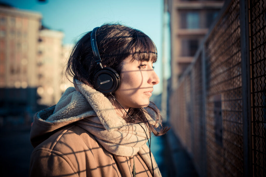A girl stands outside while wearing headphones. She is experiencing a Flakka high.
