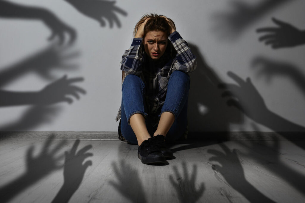 Person in the middle of a cirlce of shadow hands, wondering, "Can being cold trigger anxiety?"