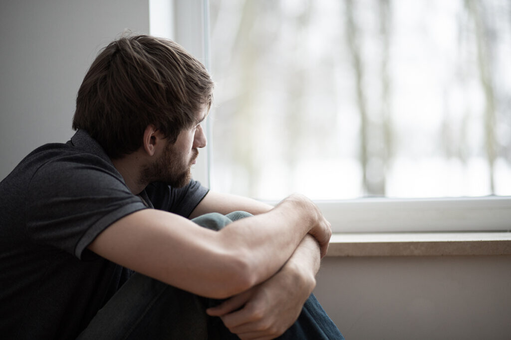 Person looking out window and wondering if drug use does cause schizophrenia