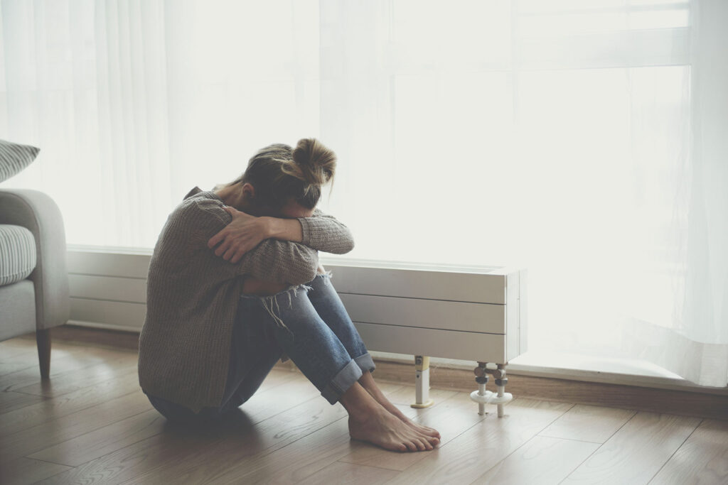 Person curling into a ball as they learn what the symptoms of untreated bipolar disorder are
