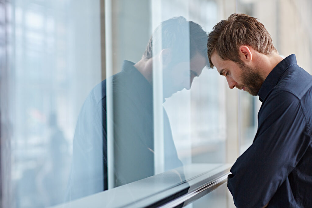 A man standing with his head against the window is experiencing the effects of meth and the brain.