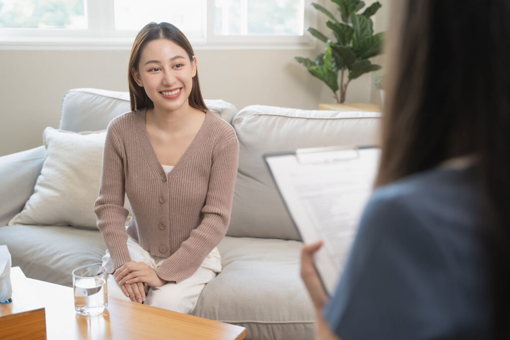 A woman is smiling while talking to her therapist. She is experiencing the benefits of psychotherapy for addiction.
