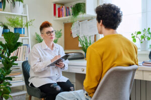 A man checks in with his therapist during his intensive outpatient program. He is visiting her office.