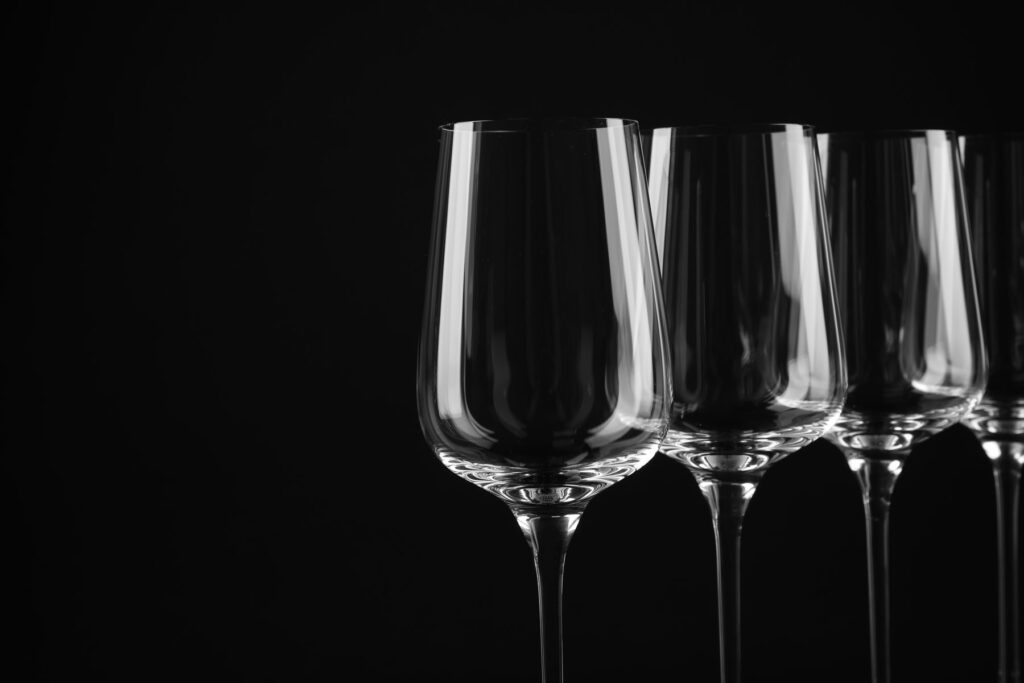 Three wine glasses stand in a row against a black background.